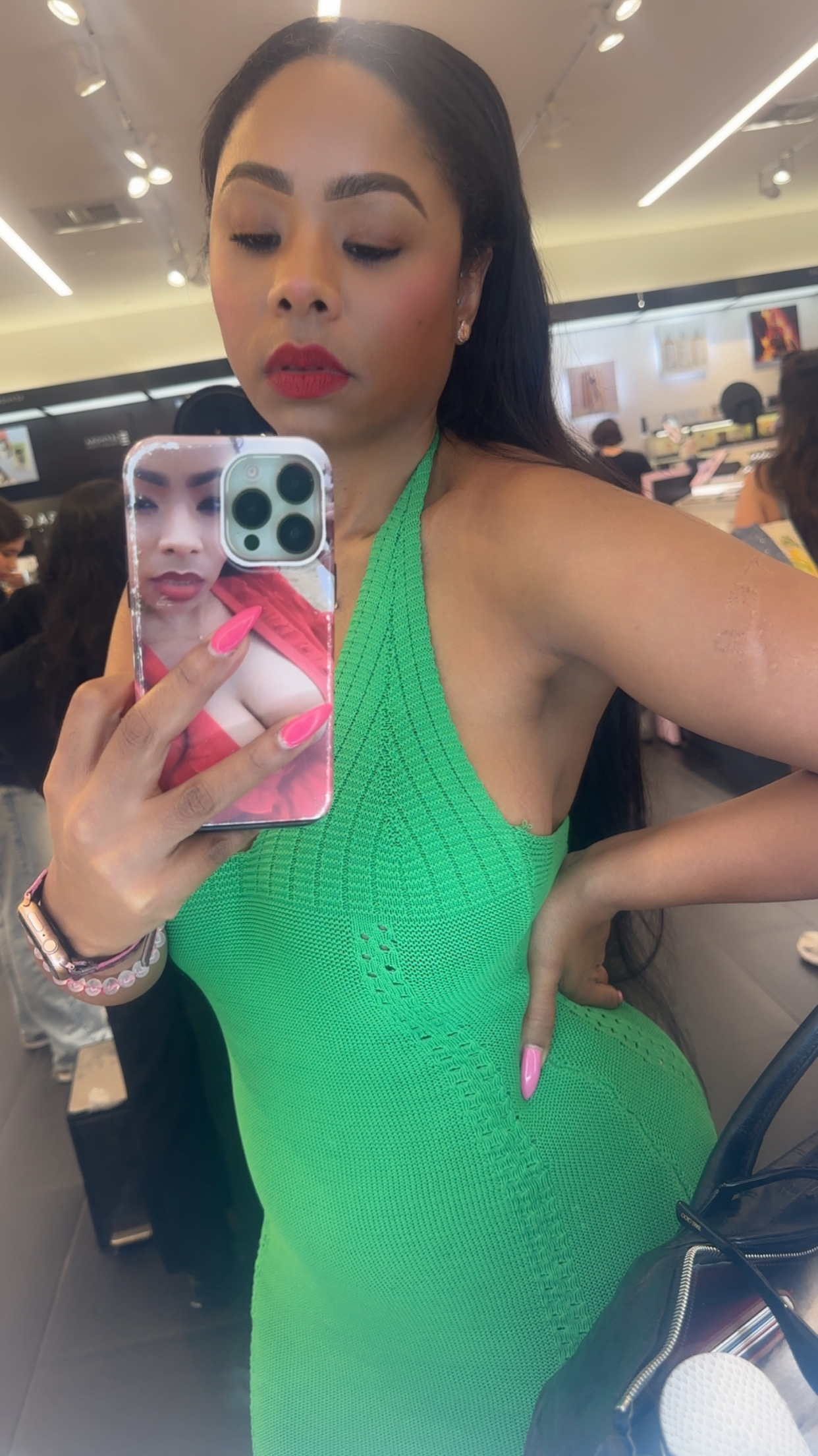 Woman in green dress taking mirror selfie.