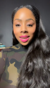 Woman with long hair, wearing camouflage top.