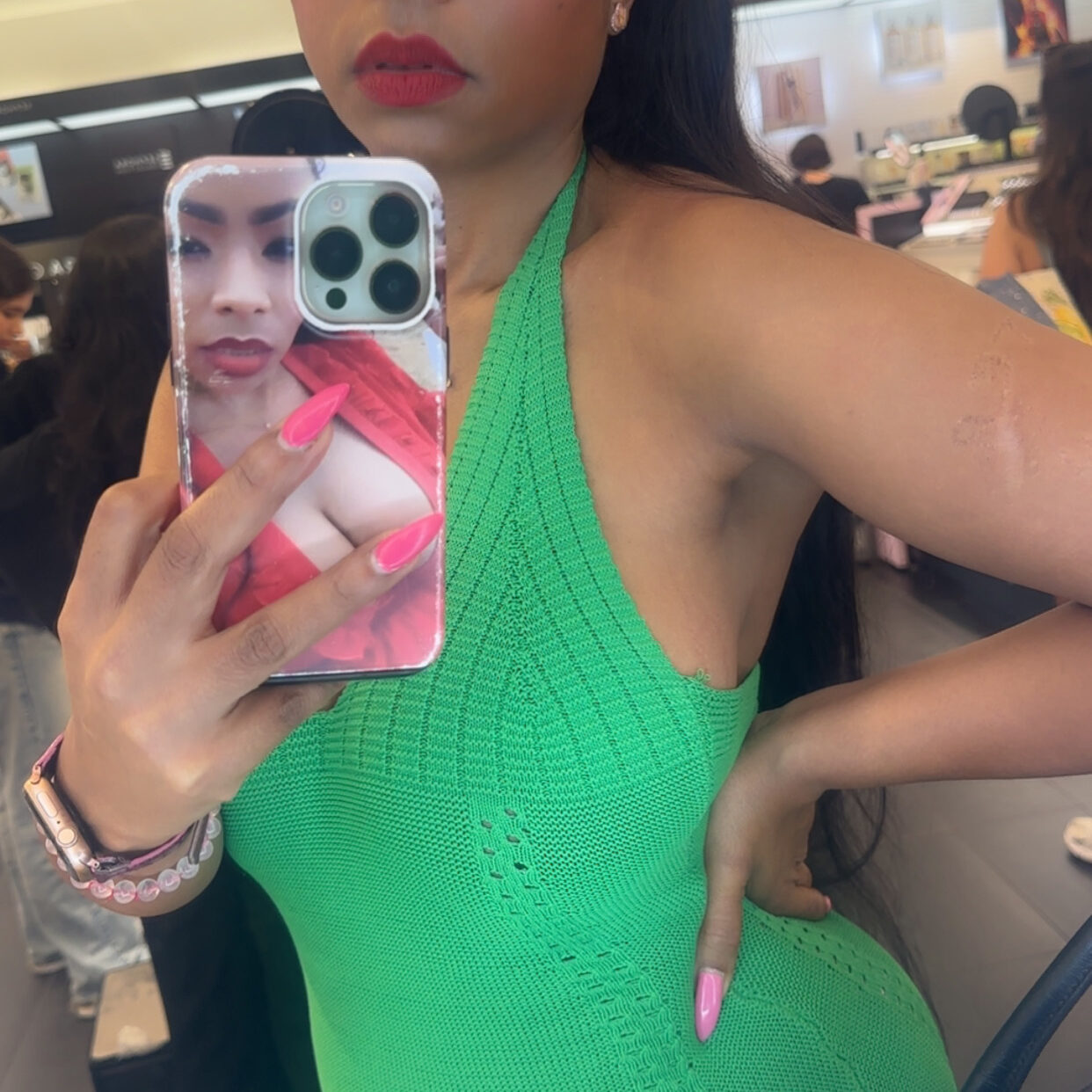 Woman in green dress taking mirror selfie.