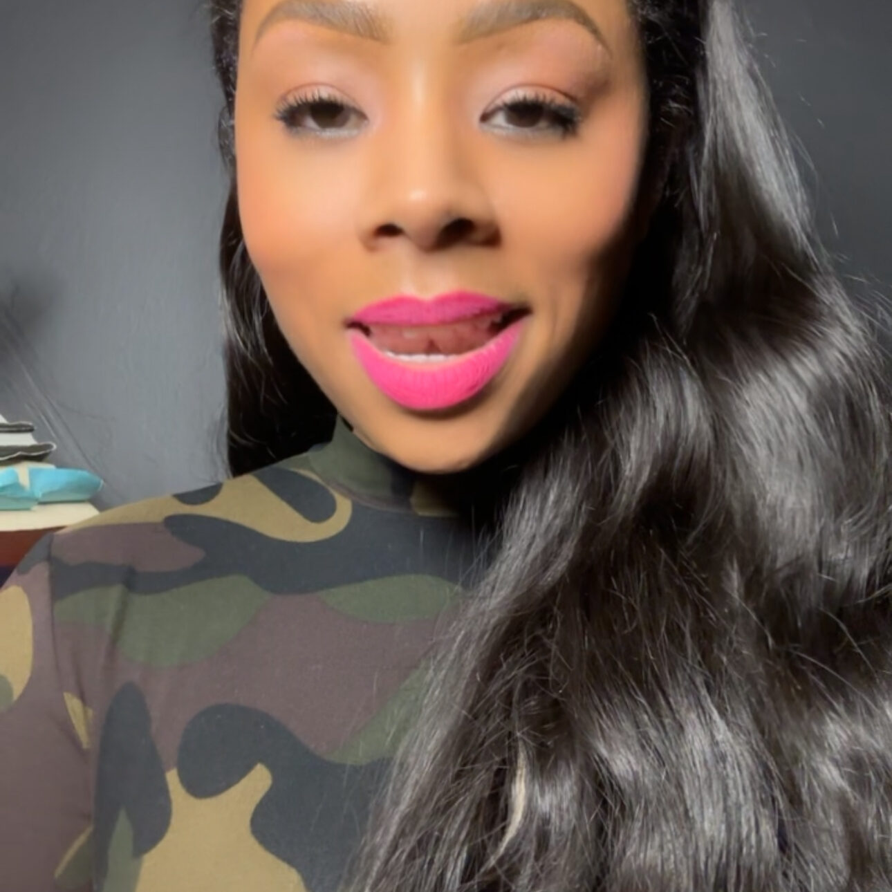 Woman with long hair, wearing camouflage top.