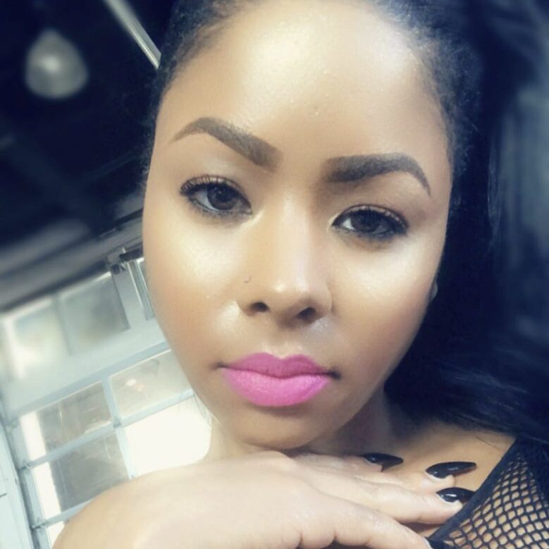 Close-up of a woman with pink lipstick and manicured nails.